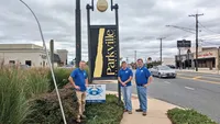 Blue Crab Fence & Home owners Jim, Brent, and Brian stand with their yard sign next to the Parkville Baltimore County sign.