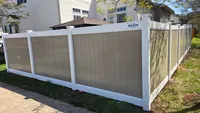 A custom two-tone vinyl privacy fence featuring khaki panels and clean white posts and top rails, installed around a Maryland residential backyard.
