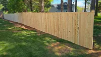 A long stretch of a premium wood privacy fence installed along the edge of a residential yard in Maryland.