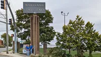 Blue Crab Fence & Home owners Jim, Brent, and Brian stand with their yard sign in front of the Maryland State Fairgrounds sign.