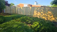 A newly built custom wood privacy fence enclosing a sunlit residential backyard in the Baltimore Metro area.