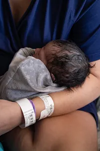 A Newborn Rests Against Their Parent.