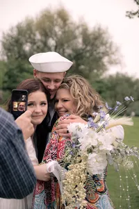 Bride and Groom hug their mother as they video call a family member after their elopement.