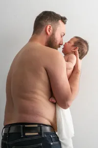 Shirtless Dad holds his baby's face close to his own in a heart-warming and intimate moment.