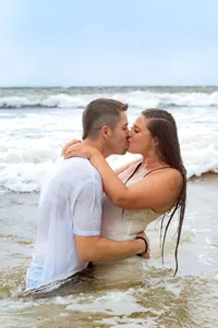 Engaged couple kissing in the ocean.