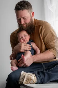 Postpartum dad holds his son in his arms.