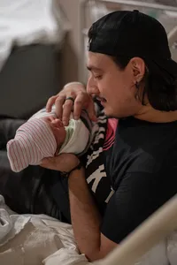 Dad holds his newborn and smiles softly at her.