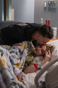 Husband kisses his wife as she rests before their daughter’s birth.