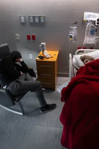 Husband and wife asleep in the hospital room as they await their baby girl's birth.