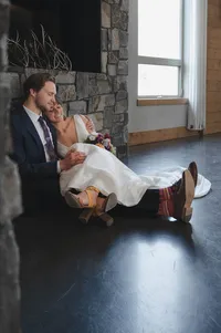 Bride and groom sitting on the floor of a quiet room as they hold each other.