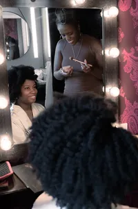 Bride and her sister smile as they do their makeup in the mirror.