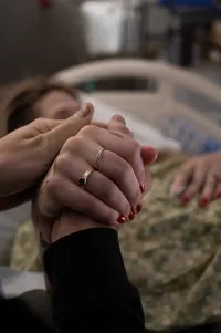 Husband holding his wife's hand as she is about to push their newborn out.