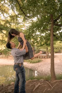Man holding his fiancé in the air from excitement after just proposing.