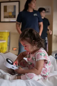 Toddler plays with the hospital bed remote while everyone meets her new sister.