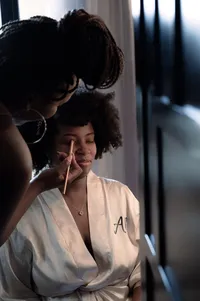 Bride sits still as she gets her makeup done for her wedding.