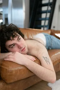 Non-binary person laying on the sofa with their boxers peeking out from their jeans.