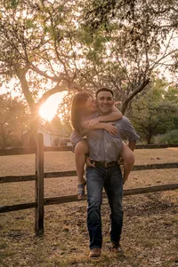 Man giving his fiancé a piggy back ride during sunset.