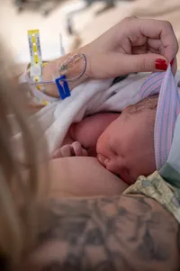 Close-up of Mom feeding her newborn and lifting her beanie to see her hair.