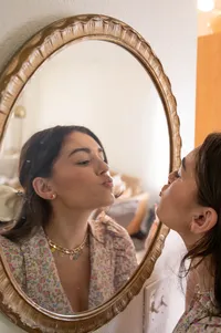 Woman goes to kiss the mirror as she checks herself out.