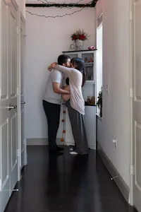 An Expectant Couple Embraces in the Hallway.