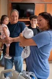 Grandma holds her newborn granddaughter up for the rest of the family to see.