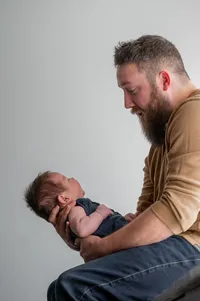 Dad sits on the windowsill and admires his baby.