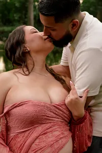 Expecting parents kissing in the creek.