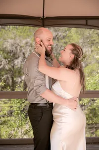 Bride grands her grooms face as they dance and laugh together.