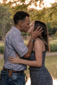 Engaged couple holding each other and kissing.