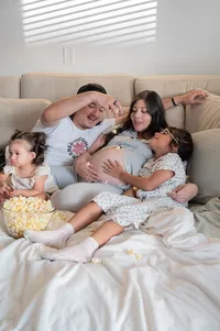Expecting mother and her family enjoying popcorn and movies while their await their newest member.