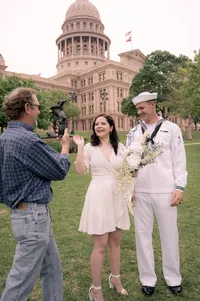 Bride and groom smiling at someone over video call after their elopement.