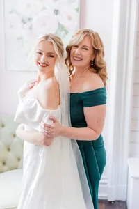 Bride wearing soft glam bridal makeup with glowing skin and lashes and a red lip with a romantic updo hairstyle