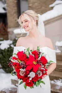 Bride wearing soft glam bridal makeup with glowing skin and lashes and a red lip with a romantic updo hairstyle