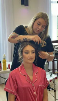 Bridal hairstylist creating a romantic updo on a bride with full glam makeup