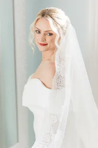 Bride wearing soft glam bridal makeup with glowing skin and lashes and a red lip with a romantic updo hairstyle