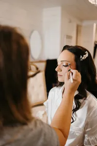 Bride having her soft glam makeup applied on her wedding morning with glam waves with hair extensions