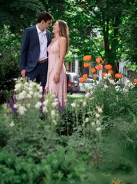 An engaged couple shares a quiet moment together beside a flower garden.