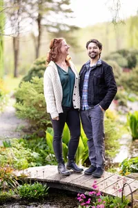 Garden An engaged couple smiles at one another while standing on a garden footbridge.