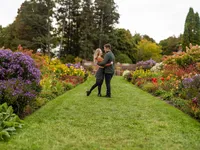Through the Garden An engaged couple holds one another in a garden surrounded by colorful flowers at Shelburne Farms.