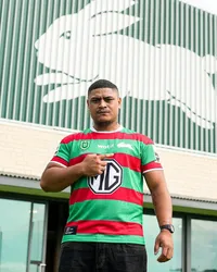 Jizza the Owner wearing a green and red rugby jersey outside a building with a rabbit mural