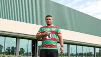 Jizza the Owner wearing a green and red rugby jersey outside a building with a rabbit mural