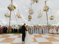 Wedding couple dancing beneath hanging floral arrangements and chandeliers