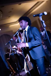 Legacy Band male vocalist performing onstage under blue lighting