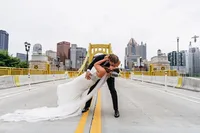 Stephen dipping Hailey for a kiss on the Roberto Clemente Bridge with the downtown Pittsburgh skyline behind them