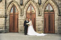 Bride and groom standing in front of tall arched wooden church doors on their wedding day