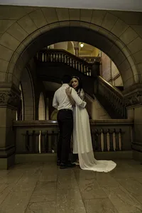 Couple embracing on a stone landing beneath a large arch inside the Allegheny County Courthouse in Pittsburgh