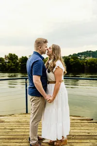 Brittany and Ben kissing on a wooden dock with the lake and trees behind them