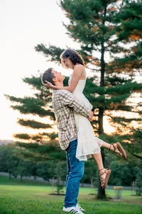 Cooper lifting Marguerite for a kiss beside a tall pine tree at golden hour