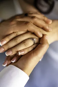 Close-up of the couple's hands resting together with her diamond ring in focus