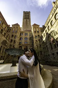 Couple embracing beside the fountain in the Allegheny County Courthouse courtyard with its stone tower behind them